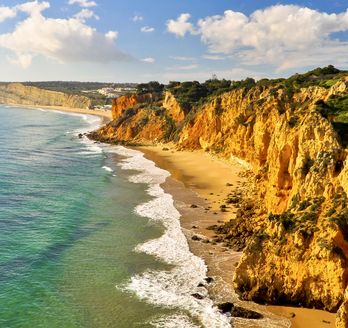Eine felsige Küstenlinie mit türkisfarbenem Wasser und einem Strand.