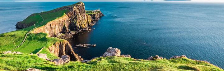 Eine felsige Insel mit einem Berg und einem alten Gebäude. Die Insel ist von blauem Wasser umgeben.
