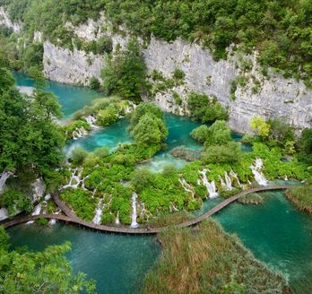 Die Plitvicer Seen in Kroatien mit türkisfarbenem Wasser, Wasserfällen und Holzstegen.