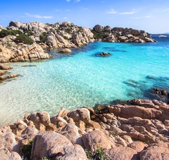 Die idyllische Cala Coticcio auf La Maddalena, Sardinien, Italien, mit türkisfarbenem Wasser, weißem Sand und felsigen Buchten, umgeben von mediterraner Vegetation.