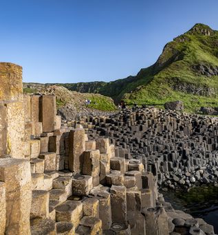Giants Causeway Stones Mit grünen Bergen im Hintergrund