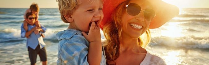 Eine Frau hält ein Kind im Arm am Strand.