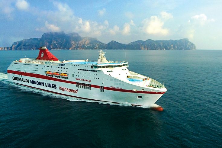 Ein großes, weißes Fährschiff mit roten Streifen und dem Logo "Minoan Lines" auf dem Schornstein fährt auf einem ruhigen blauen Meer.