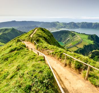 Eine grüne, hügelige Landschaft mit einem Pfad, der sich durch die Hügel schlängelt.