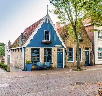 Ein blaues Haus mit einem Garten und einem Zaun.