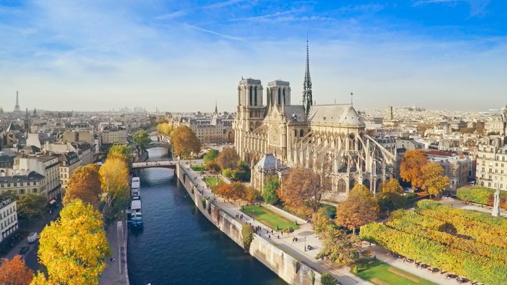 Eine Luftaufnahme von Paris mit dem Eiffelturm, der Seine und Gebäuden. Die Stadt erstreckt sich weitläufig und zeigt ihre ikonischen Wahrzeichen.