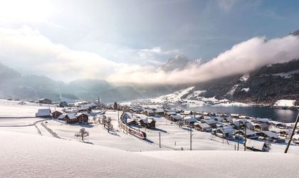 Verschneites Dorf, das am See liegt
