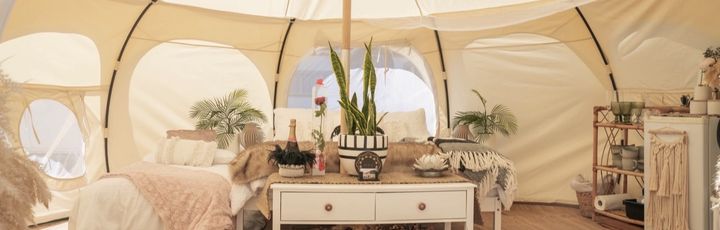 Gemütlicher Innenraum eines Glamping-Zeltes mit Bett, Teppich und Dekoration.