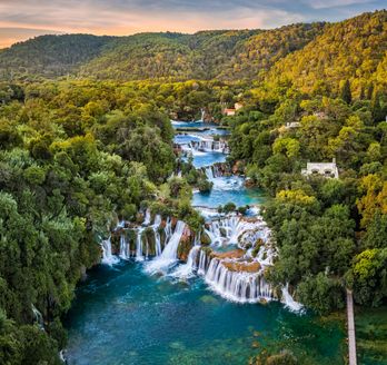 Ein Wasserfall, der in einen See fließt, umgeben von grüner Vegetation.