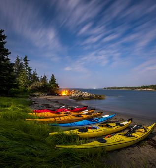 Kajaks am Strand der  Cape LaHave Islands in der Dämmerung im Hintergrund brennt ein Lagerfeuer
