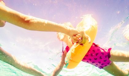 Mujtter und Kind im rosa Badeanzug und gelbem Schwimmreifen.