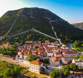 Eine Stadtansicht mit roten Dächern und Bergen.