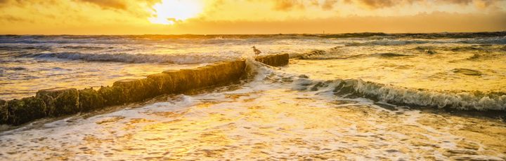 Strand mit Wellen bei Sonnenuntergang.