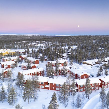 Verschneite rote Häuser im Wald in Finnland