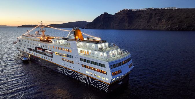 Kreuzfahrtschiff fährt durch das Meer mit Berg im Hintergrund