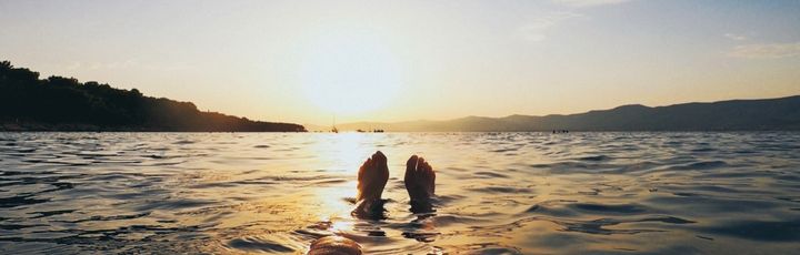 Zwei Personen schwimmen im Meer bei Sonnenuntergang.