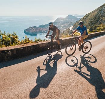 Zwei Personen fahren Fahrrad auf einem Weg mit Blick auf die Stadt.