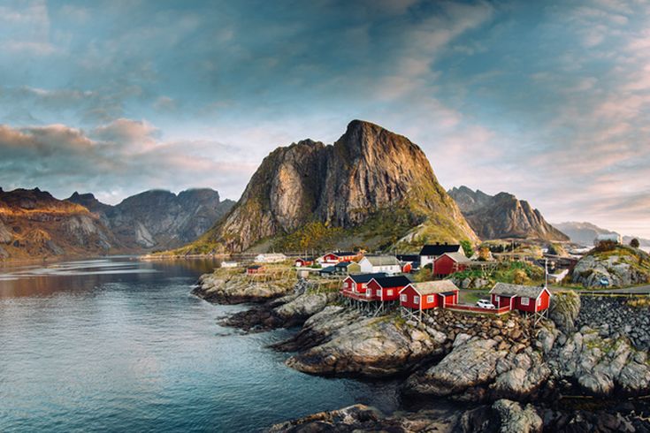 Eine malerische Küstenlandschaft der Lofoten in Norwegen mit einem Dorf und Bergen.