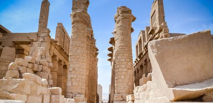 Eine archäologische Stätte in Luxor, die von einer großen Säulenreihe und alten Strukturen umgeben ist.