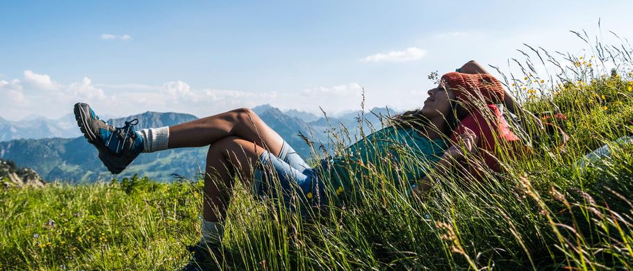Wanderer liegt auf Wiese in den Bergen