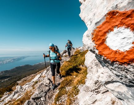Eine Person klettert auf einen Felsen mit Blick auf eine weite Landschaft.