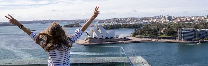 Frau schaut auf Sidney und streckt ihre Arme nach oben
