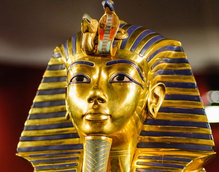 Eine Nahaufnahme zeigt die goldene, mit blauen Lapislazuli-Streifen verzierte Totenmaske des Pharaos Tutanchamun.