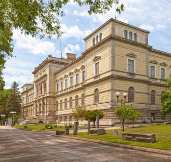 Archäologisches Museum in Varna, Blick von der Straße auf das hübsche Gebäude. Weg ist mit Gras und Bäumen geebnet.