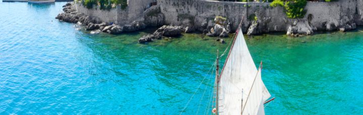 Ein Segelboot im Hafen von Krk, Kroatien, mit der Altstadt im Hintergrund.