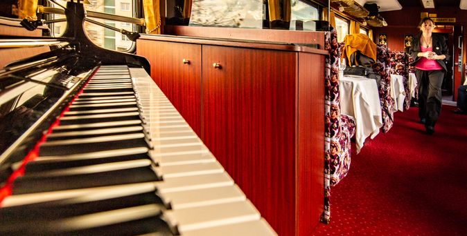 Blick über die Klaviertastatur in den Speisesaal des Gotthard Nostalgie Express