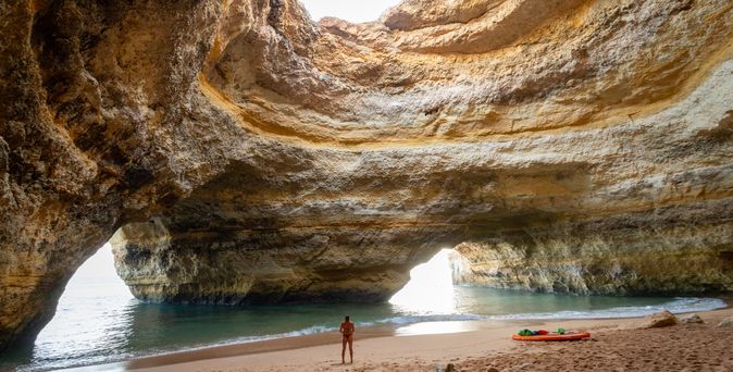 Grotte von Benagli Frau steht am Strnd Paddelboaud liegt im Sand