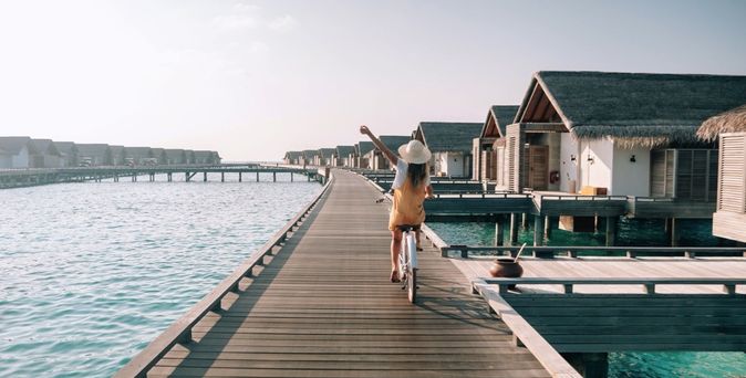 Eine Frau fährt Fahrrad auf einem Holzsteg über dem Wasser.