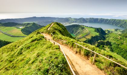 Eine grüne, hügelige Landschaft mit einem Pfad, der sich durch die Hügel schlängelt.