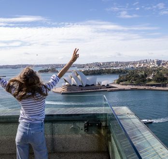 Frau schaut auf Sidney und streckt ihre Arme nach oben