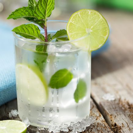 Ein Glas Mojito mit Limetten und Minze.