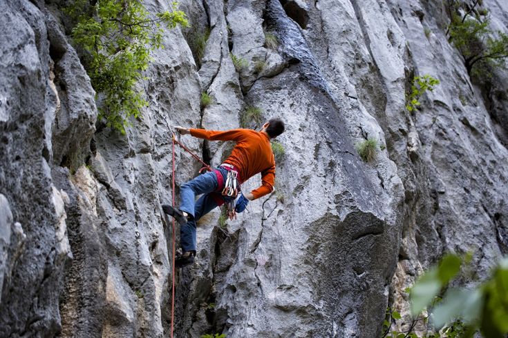 Eine Person klettert an einem Felsen hinauf.