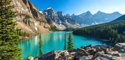 Aussagekräftige Berglandschaft, inmitten ein türkisblauer See und rundherum einige Bäume.