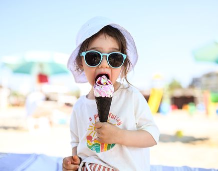 KLeinkind sitzt am strand und isst ein eis