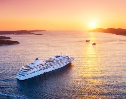 Kreuzfahrtschiff auf offenem Meer fährt in den Sonnenuntergan
