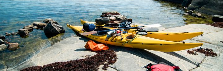 Eine Küstenlandschaft mit Booten am Ufer und gelben Kajaks.