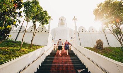 Zwei Menschen besteigen Treppen zu weißem Tempel