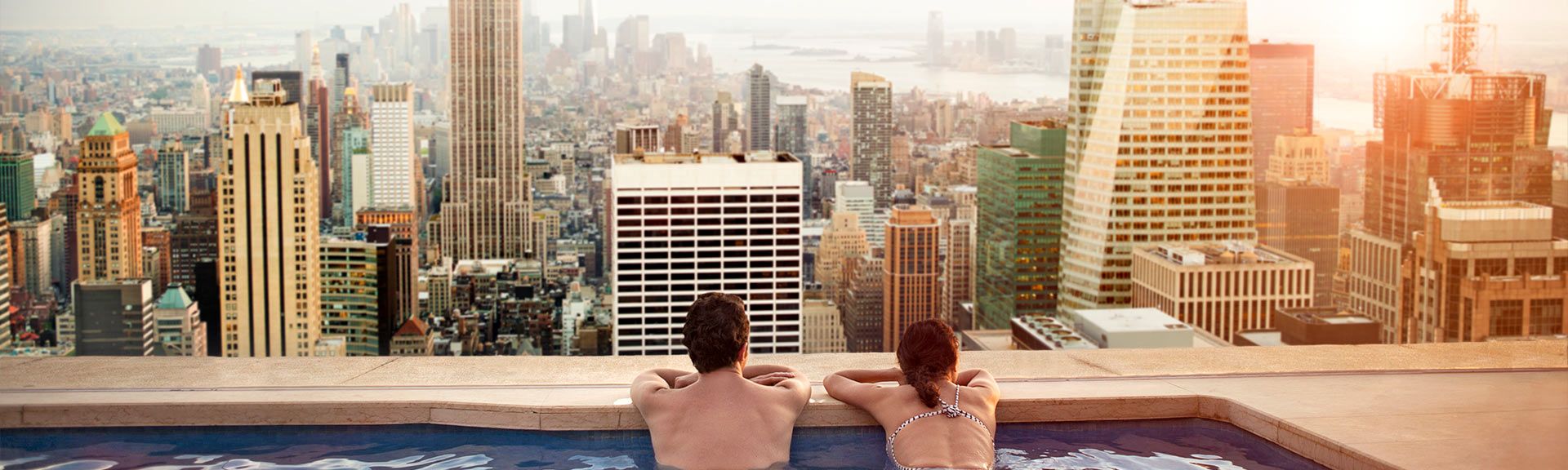 Paar blickt im Infinity-Pool über eine Großstadt 