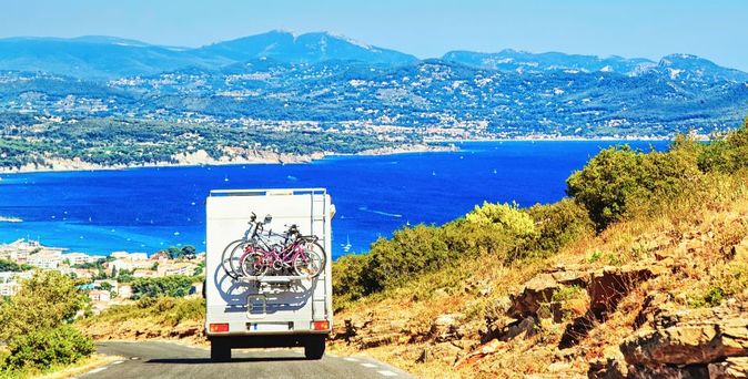 Ein Wohnmobil fährt auf einer Küstenstraße.