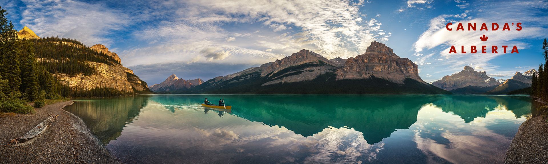 Zwei Personen sitzen in eine Kanu auf einem See vor einer fantastischen Bergkulisse