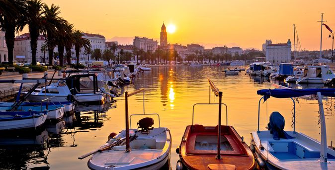 Ein Hafen in Split, Kroatien, mit Booten und Gebäuden bei Sonnenuntergang.