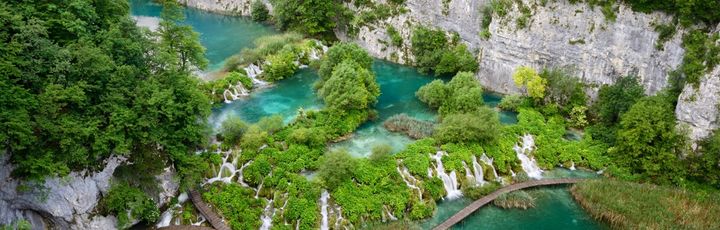 Die Plitvicer Seen in Kroatien mit türkisfarbenem Wasser, Wasserfällen und Holzstegen.