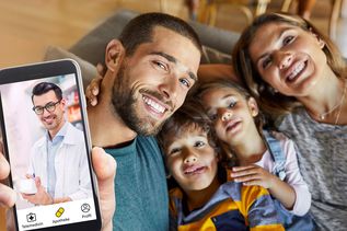 Familie bei einer Telemedizin-Videoberatung: Vater hält Smartphone mit Arzt im Videoanruf, Mutter und zwei Kinder lächeln daneben.