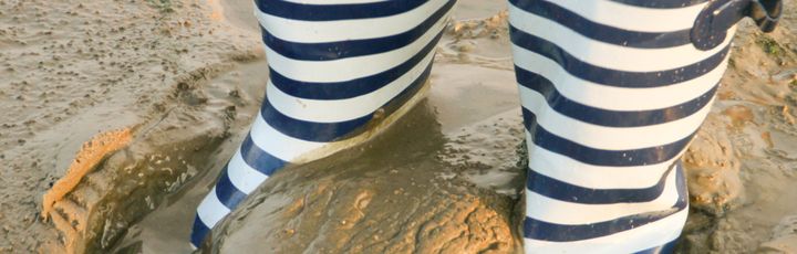 Eine Person trägt gestreifte Hosen und ist teilweise im Sand vergraben.