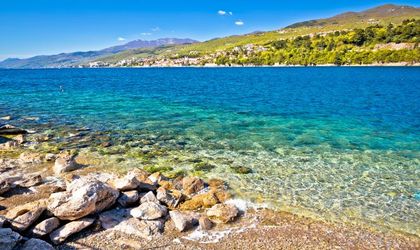 Ein Sandstrand mit türkisfarbenem Wasser und einer Küstenlinie.