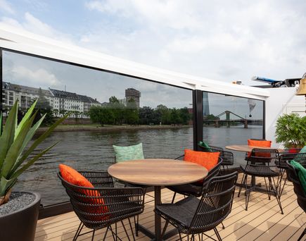 Ein elegantes Restaurant auf einem Schiff mit gedeckten Tischen und Blick nach draußen.